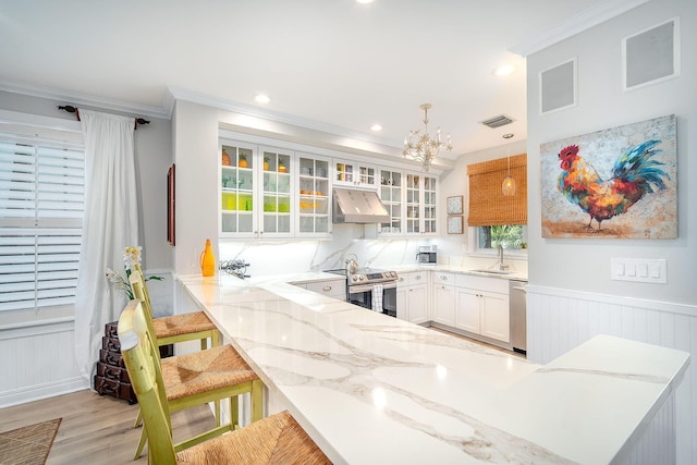 kitchen with a kitchen bar, white cabinetry, hanging light fixtures, kitchen peninsula, and stainless steel appliances