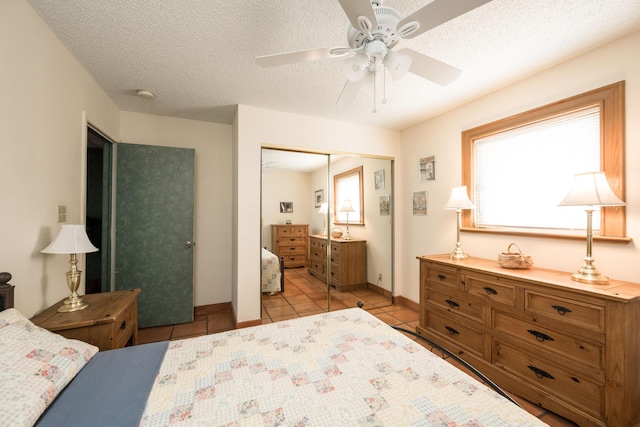 tiled bedroom with ceiling fan, a closet, and a textured ceiling