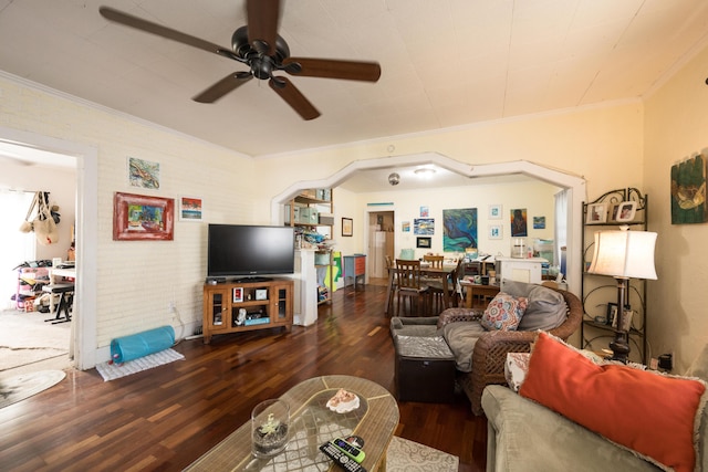 living room with arched walkways, a ceiling fan, brick wall, ornamental molding, and wood finished floors