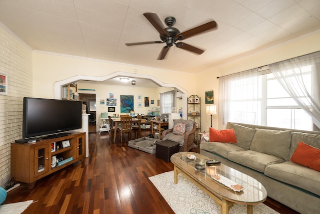 living room featuring arched walkways, brick wall, a ceiling fan, wood-type flooring, and crown molding