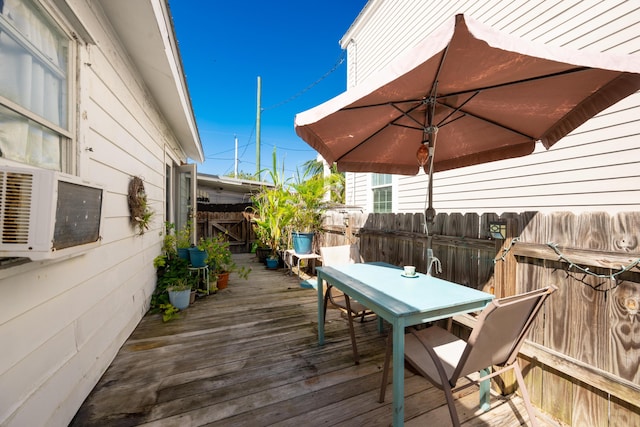 wooden terrace with outdoor dining space, cooling unit, and fence