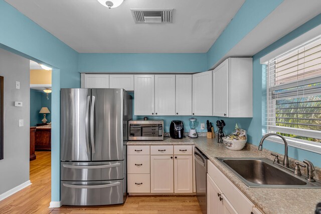 kitchen with white cabinetry, sink, stainless steel appliances, and light wood-type flooring