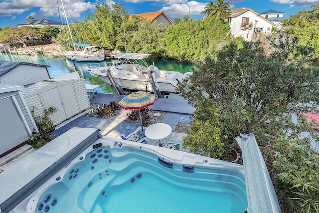 view of swimming pool with a dock, a hot tub, and a water view