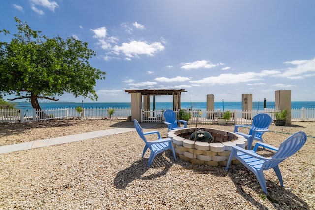 view of property's community with a water view, a fire pit, and fence