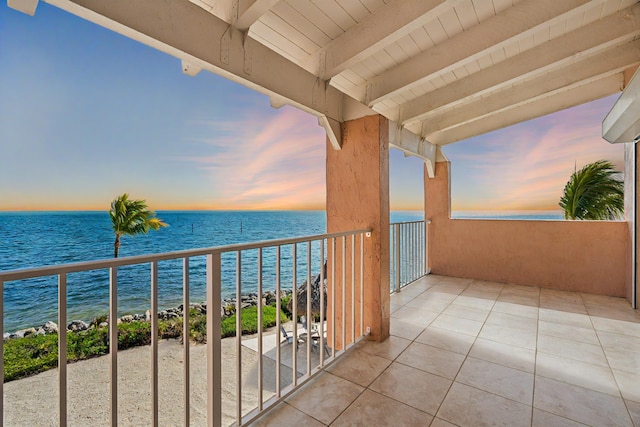 balcony at dusk featuring a water view