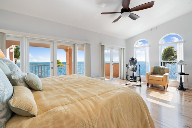 bedroom with french doors, access to exterior, a water view, light hardwood / wood-style floors, and vaulted ceiling