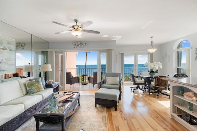 living room featuring ceiling fan, a water view, and light hardwood / wood-style flooring