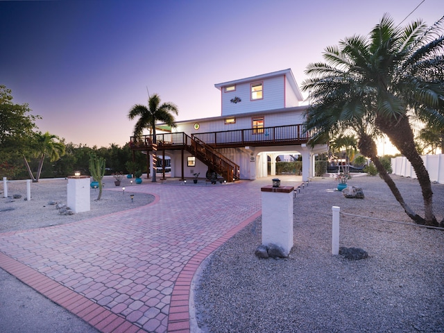 exterior space with a deck, curved driveway, fence, stairway, and a patio area