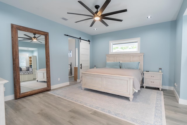 bedroom with recessed lighting, visible vents, light wood-style flooring, a barn door, and baseboards