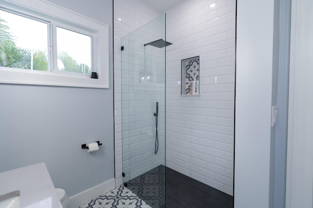 bathroom with walk in shower, toilet, and baseboards