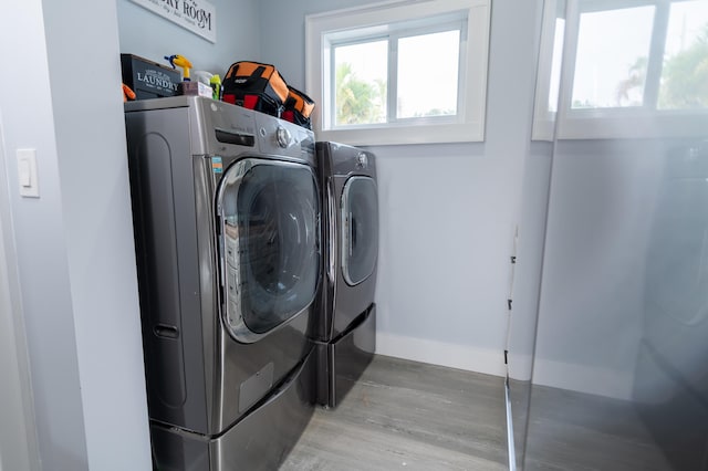 washroom featuring laundry area, baseboards, wood finished floors, and washing machine and clothes dryer