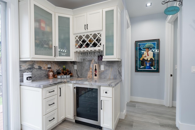 bar featuring baseboards, a bar, wine cooler, and decorative backsplash