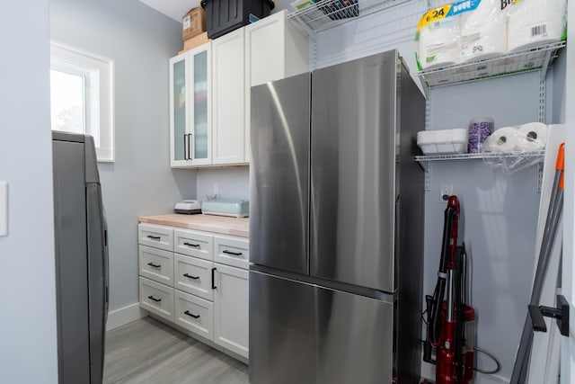 kitchen featuring light wood-style flooring, glass insert cabinets, freestanding refrigerator, fridge, and white cabinetry