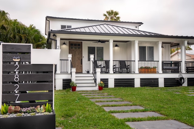 view of front of house with covered porch, metal roof, stairs, and a front yard