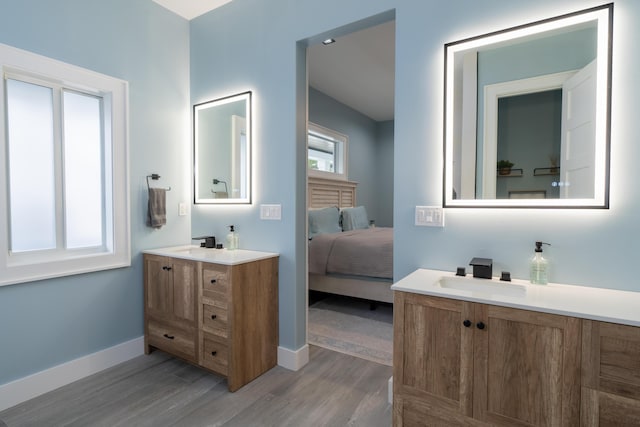 ensuite bathroom featuring connected bathroom, vanity, baseboards, and wood finished floors