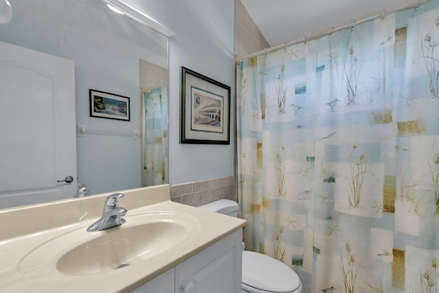 bathroom featuring walk in shower, vanity, toilet, and tile walls