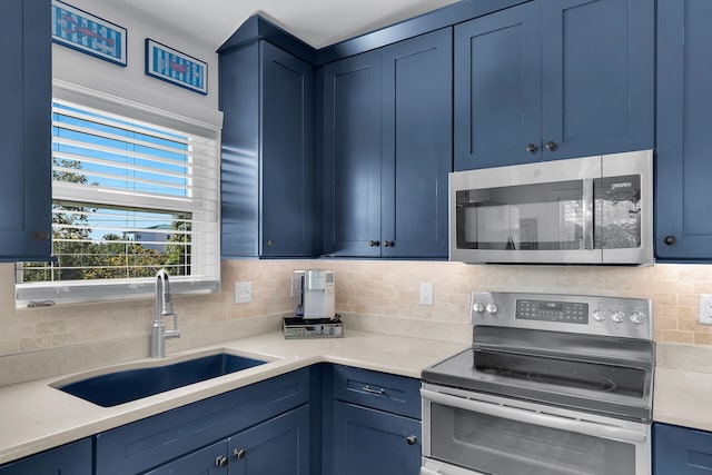 kitchen featuring stainless steel appliances, sink, backsplash, and blue cabinetry