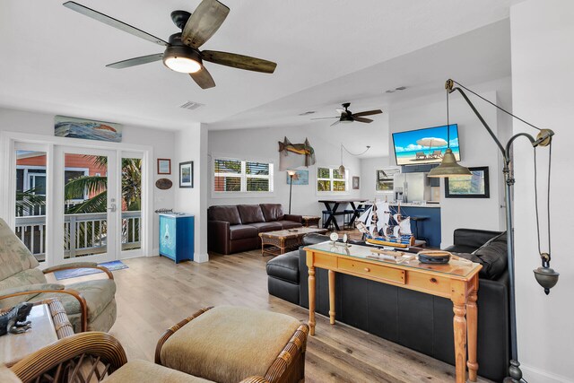 living room with lofted ceiling, ceiling fan, and light wood-type flooring