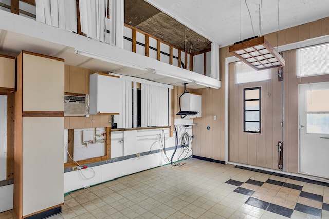 interior space featuring pendant lighting, wooden walls, and a wall unit AC