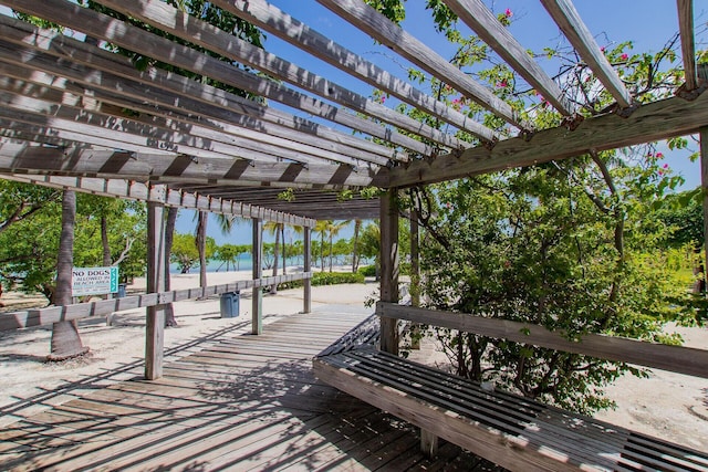 wooden deck with a water view and a pergola