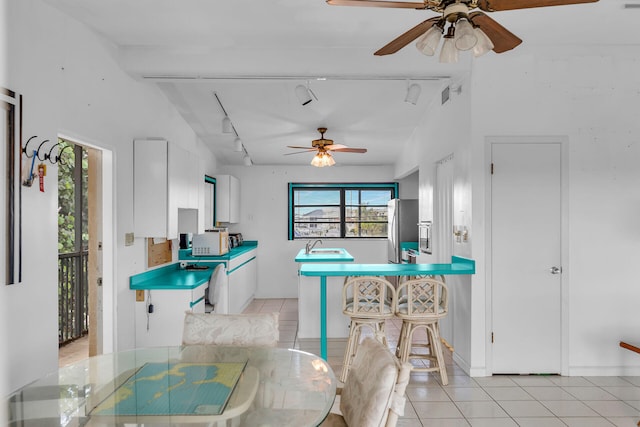 kitchen featuring rail lighting, stainless steel refrigerator, white cabinets, and light tile patterned flooring