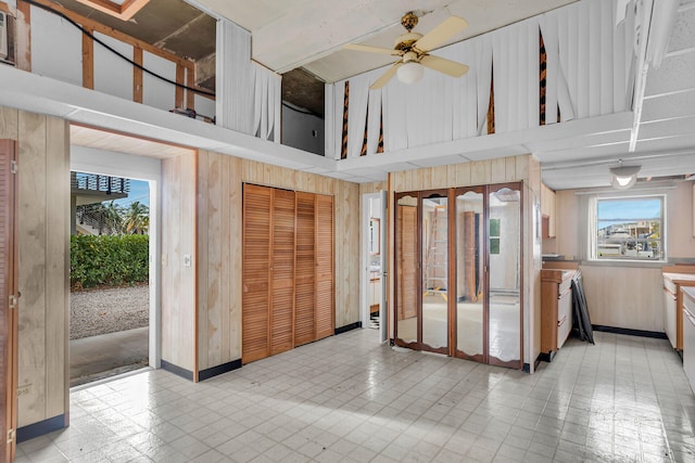 kitchen featuring ceiling fan, wood walls, and a high ceiling