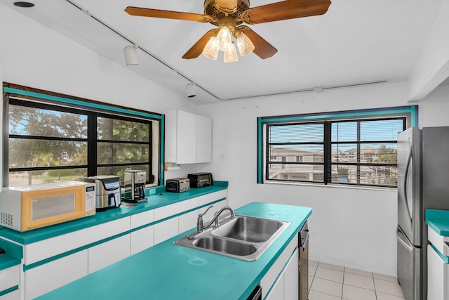 kitchen with white cabinetry, rail lighting, sink, stainless steel fridge, and light tile patterned floors