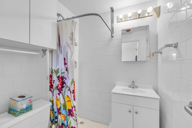 bathroom featuring walk in shower, vanity, toilet, and tile walls