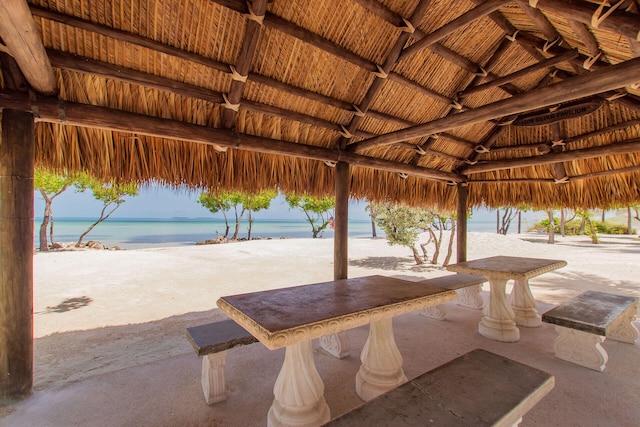 view of patio / terrace with a gazebo, a water view, and a beach view