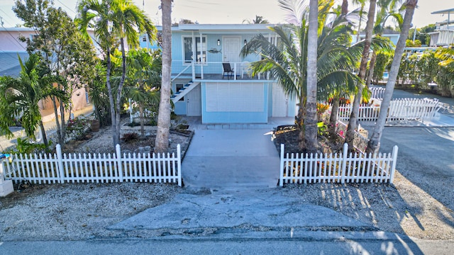 162 Azalea St, Tavernier, FL 33070 - view of front facade with stairway, covered porch, and a fenced front yard