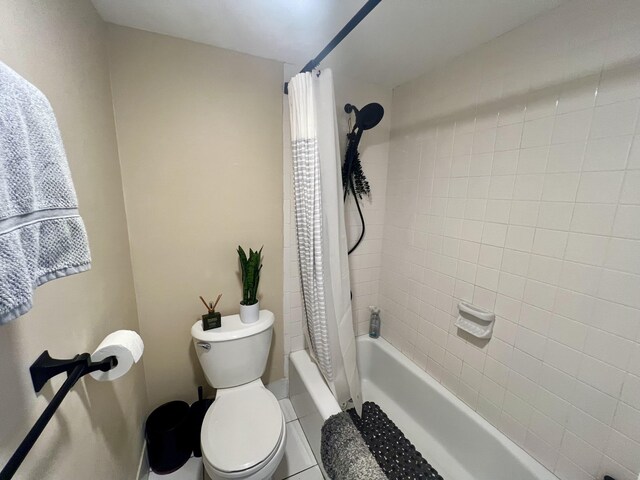 bathroom with shower / tub combo with curtain, tile patterned floors, and toilet