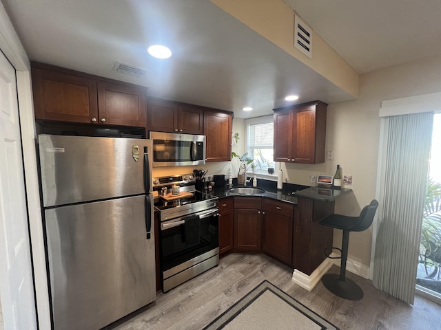 kitchen featuring dark brown cabinetry, stainless steel appliances, sink, and light wood-type flooring