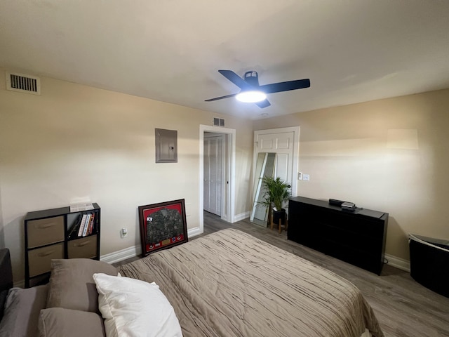 bedroom with electric panel, ceiling fan, and light wood-type flooring