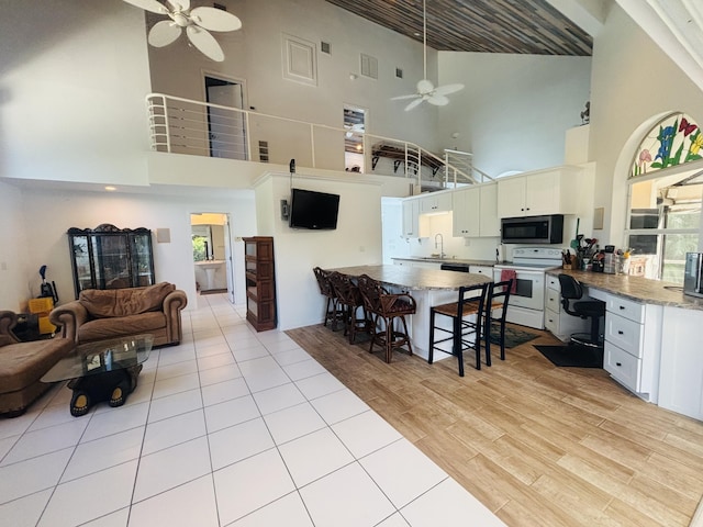 kitchen with sink, white cabinets, electric range, ceiling fan, and light hardwood / wood-style flooring