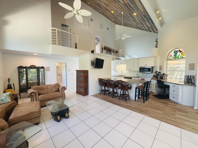 living room featuring sink, light tile patterned floors, and ceiling fan