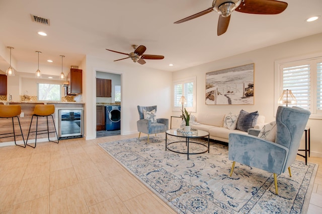 living room with washer / clothes dryer, sink, beverage cooler, and ceiling fan