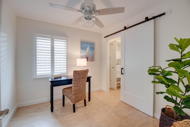 office space featuring ceiling fan, a barn door, and light hardwood / wood-style flooring