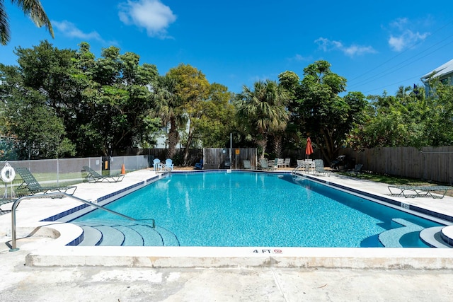 community pool with a patio area and fence