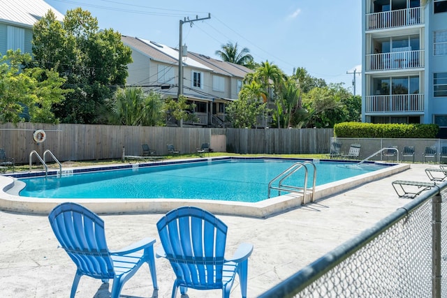 community pool with a patio area and fence