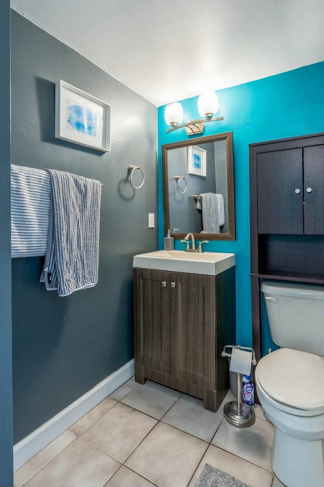 bathroom featuring toilet, vanity, baseboards, and tile patterned floors