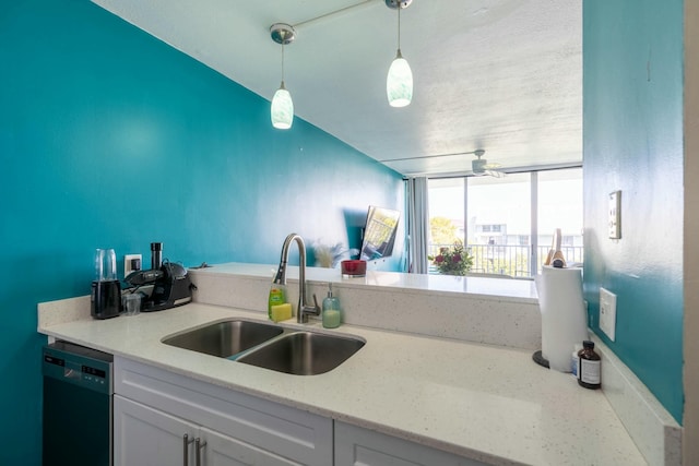 kitchen with dishwashing machine, light stone counters, a sink, white cabinets, and pendant lighting