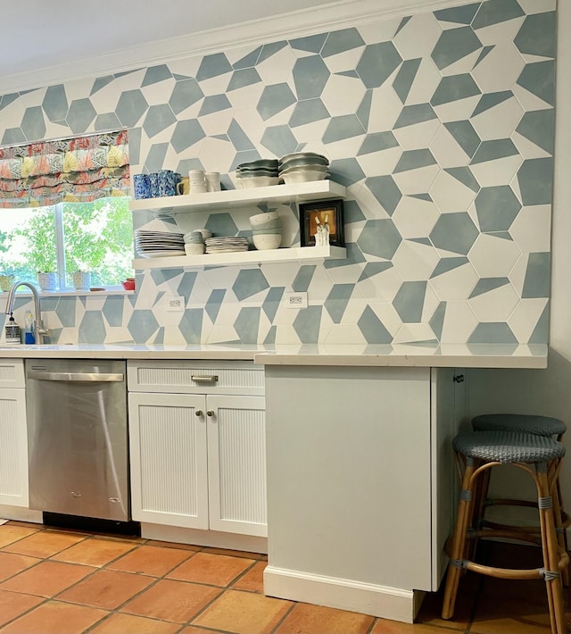 kitchen featuring light tile patterned flooring, stainless steel dishwasher, white cabinets, and crown molding