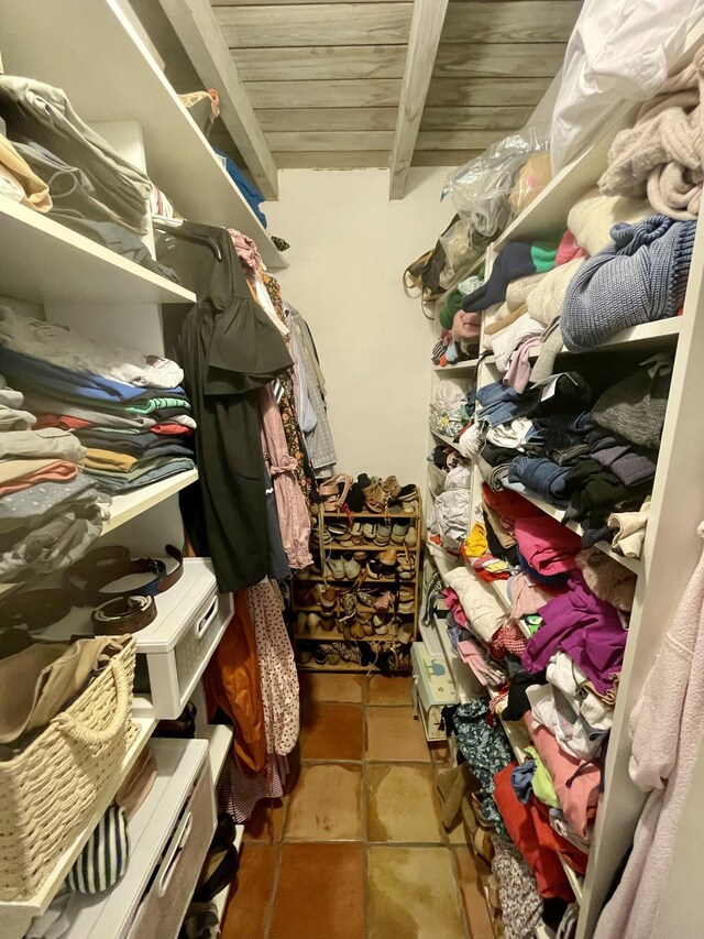 walk in closet with beam ceiling and tile patterned floors