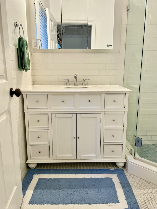 bathroom with a shower with door, vanity, tile walls, and backsplash