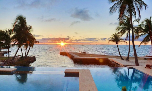 pool at dusk featuring a water view