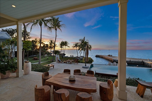 patio terrace at dusk featuring a water view