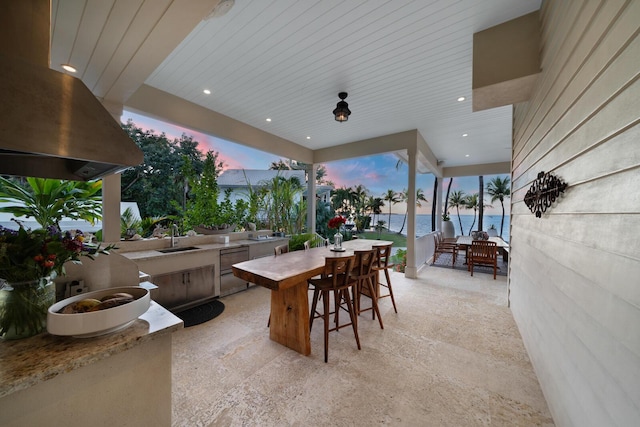 patio terrace at dusk featuring a water view and sink