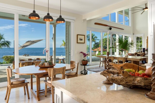 dining room featuring ceiling fan and a water view