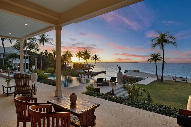 patio terrace at dusk with a lawn and a water view