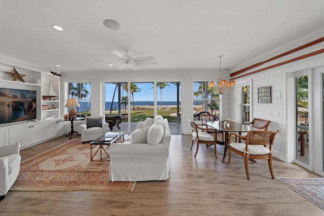 living room featuring ceiling fan with notable chandelier, a wealth of natural light, and light wood-type flooring